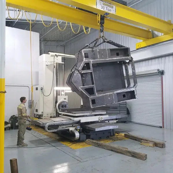 Large weldment set up on a CNC boring mill under a 30-ton crane