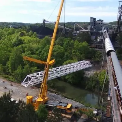 Crane lifting a fabricated conveyor bridge truss into place