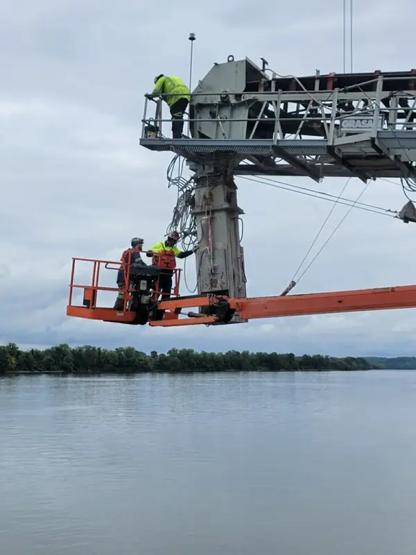 Field crew working from a lift on a riverside conveyor installation