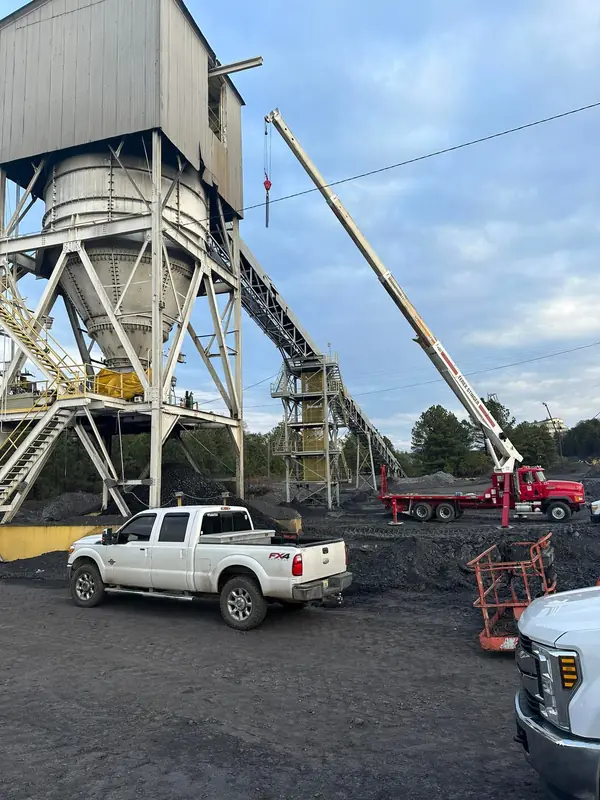 Field crew and boom truck at a plant conveyor