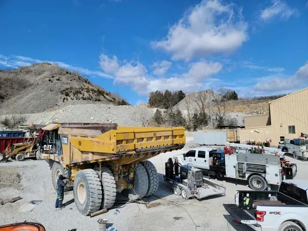 Field service trucks repairing a haul truck at a quarry