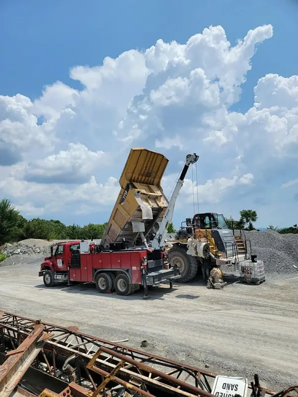 Boom truck lifting a haul truck bed for repair
